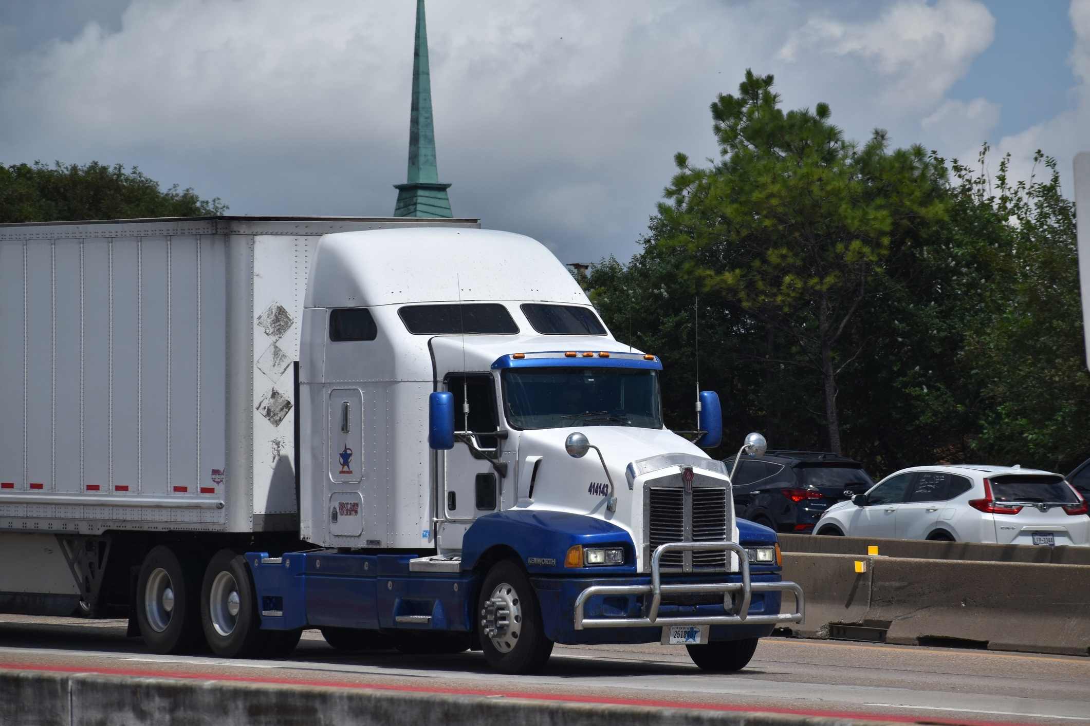 White and blue semi-truck on a Texas highway, representing a Baytown truck accident lawyer.