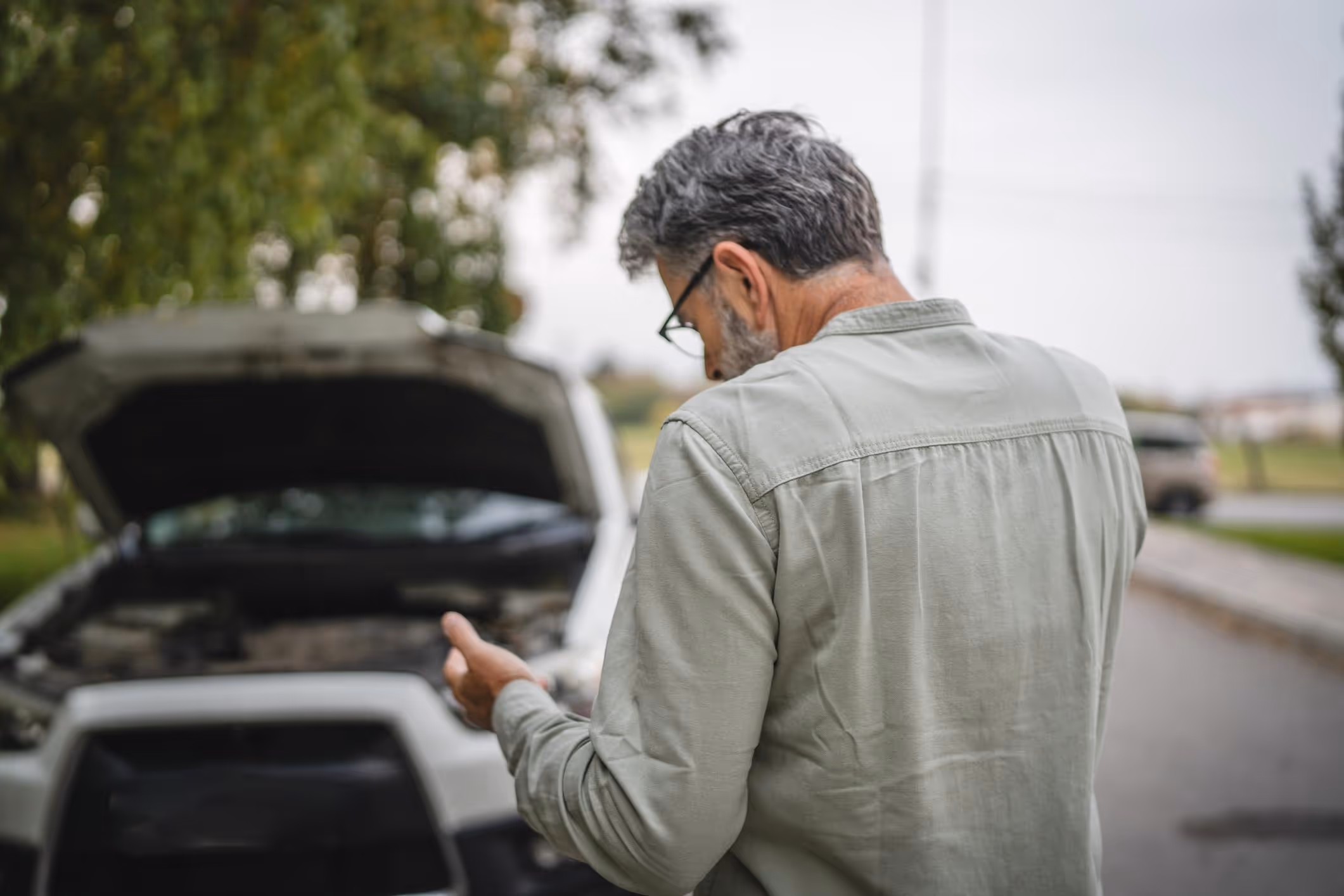 Worried driver examines car damage after crash while considering a Missouri City car accident lawyer.