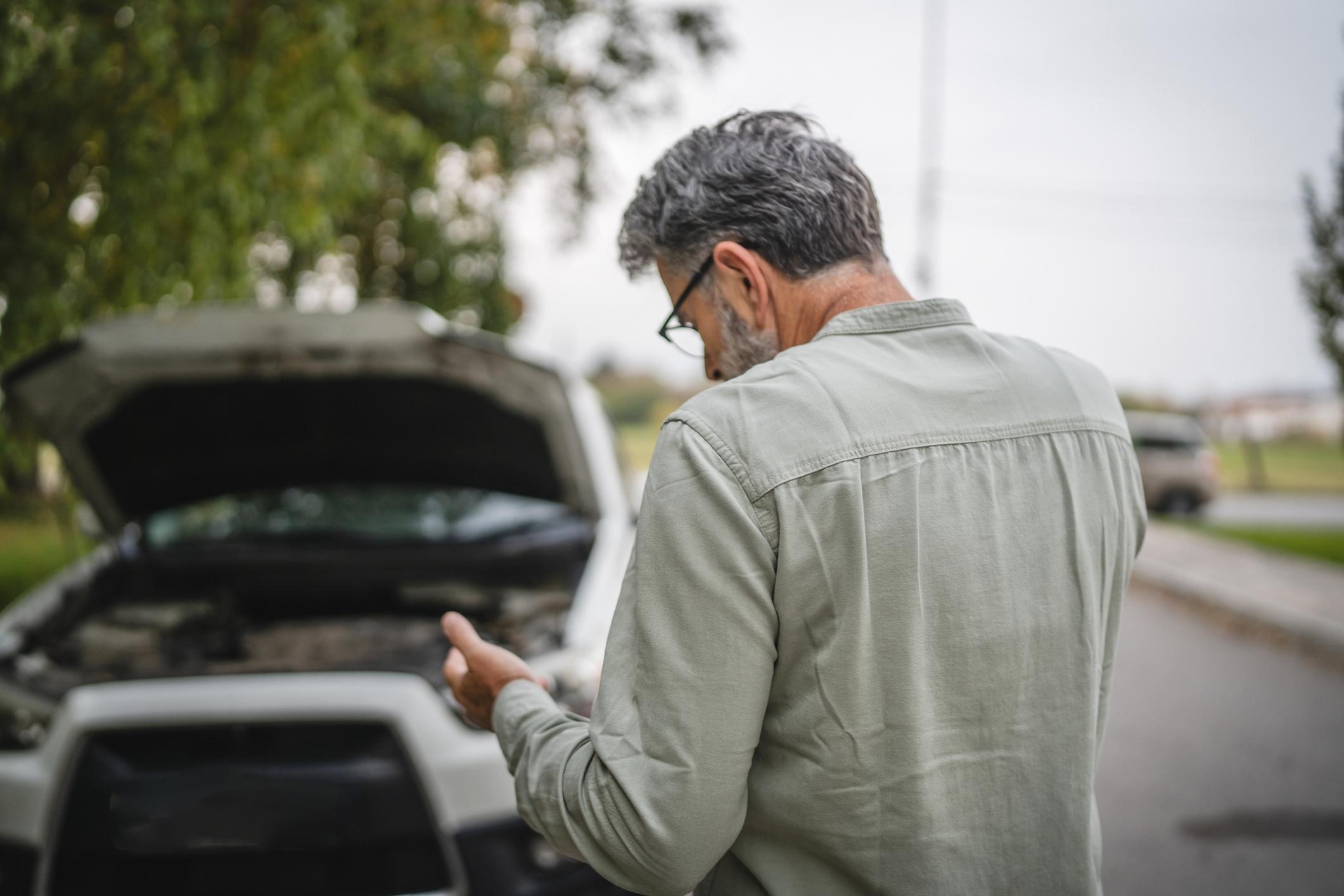 Worried driver examines car damage after crash while considering a Missouri City car accident lawyer.