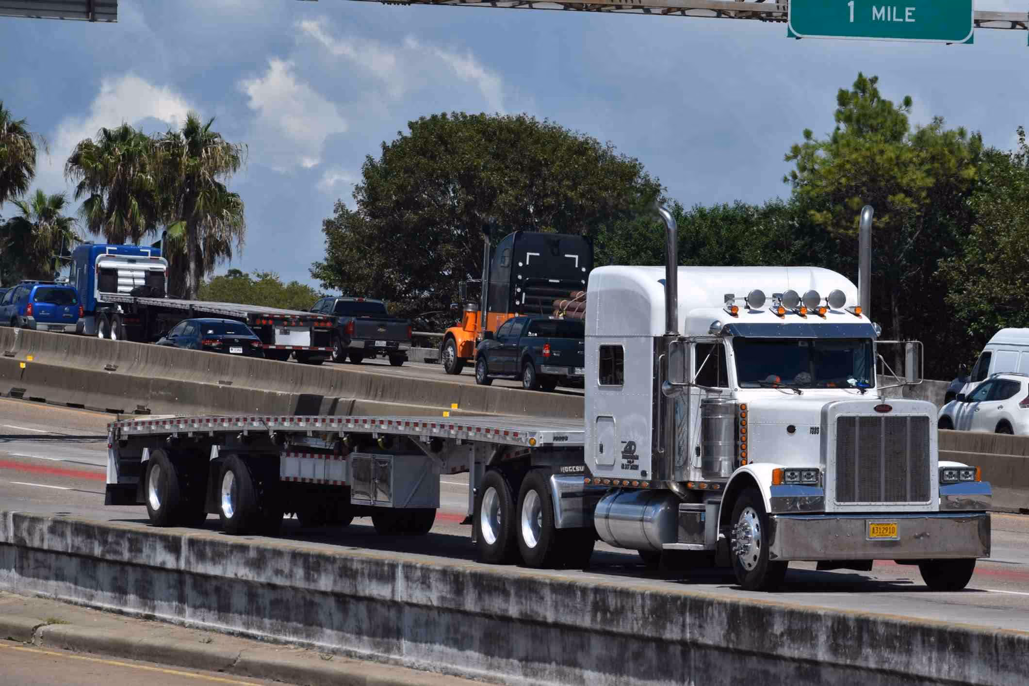 Flatbed truck on busy I-45 highway near League City, demonstrating the trucking traffic that leads to serious accidents needing a League City truck accident lawyer.