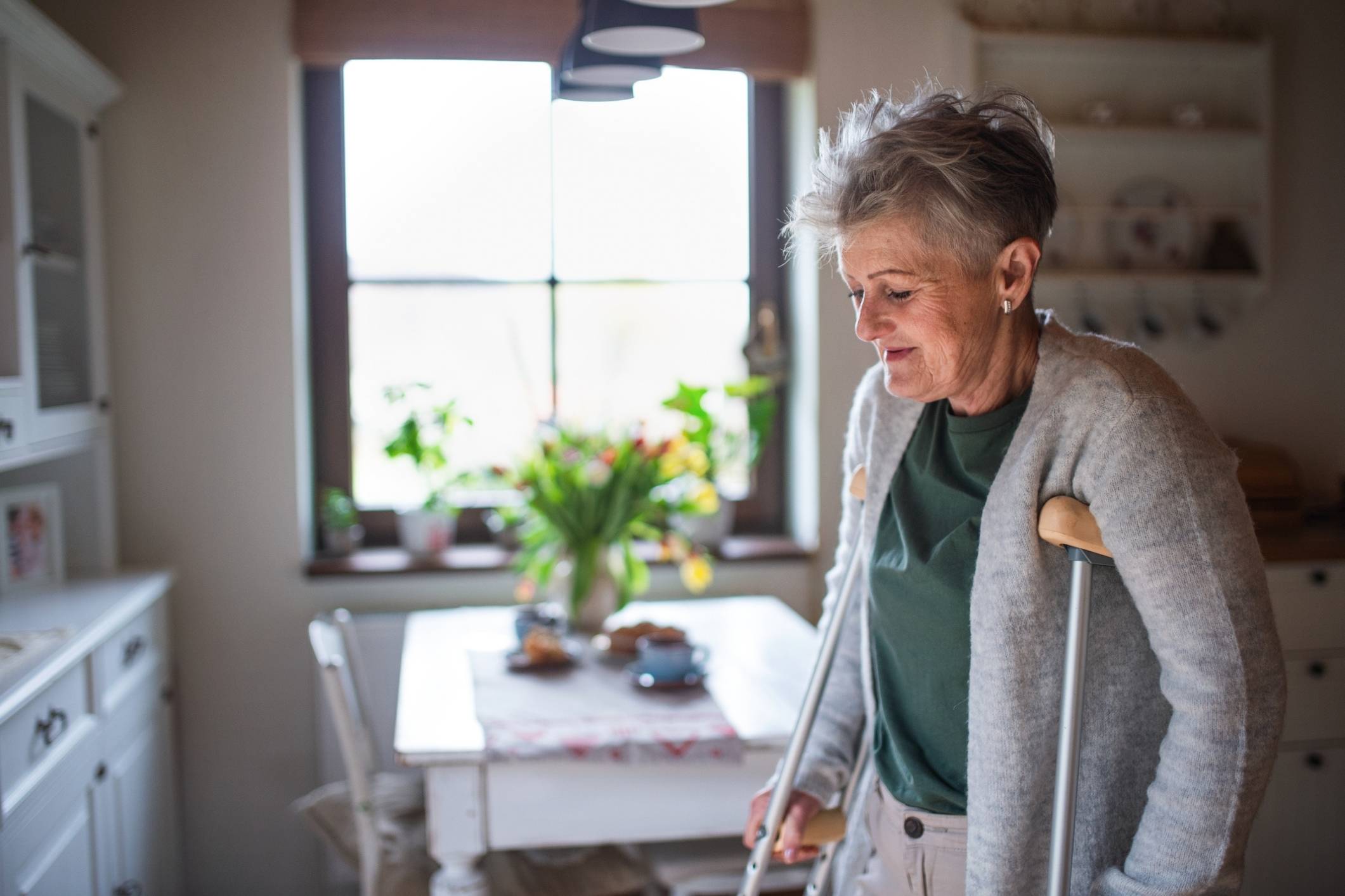 Senior woman using crutches at home, representing Houston personal injury lawyer.