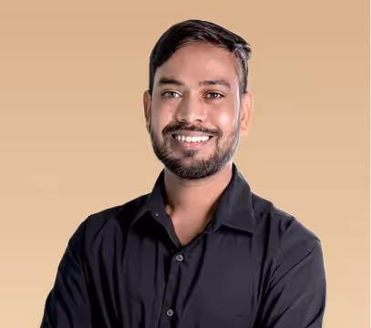 Smiling man with short dark hair and beard wearing a black shirt against a beige background.