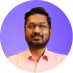 Portrait of a man with glasses and a beard wearing a pale pink shirt against a purple background.