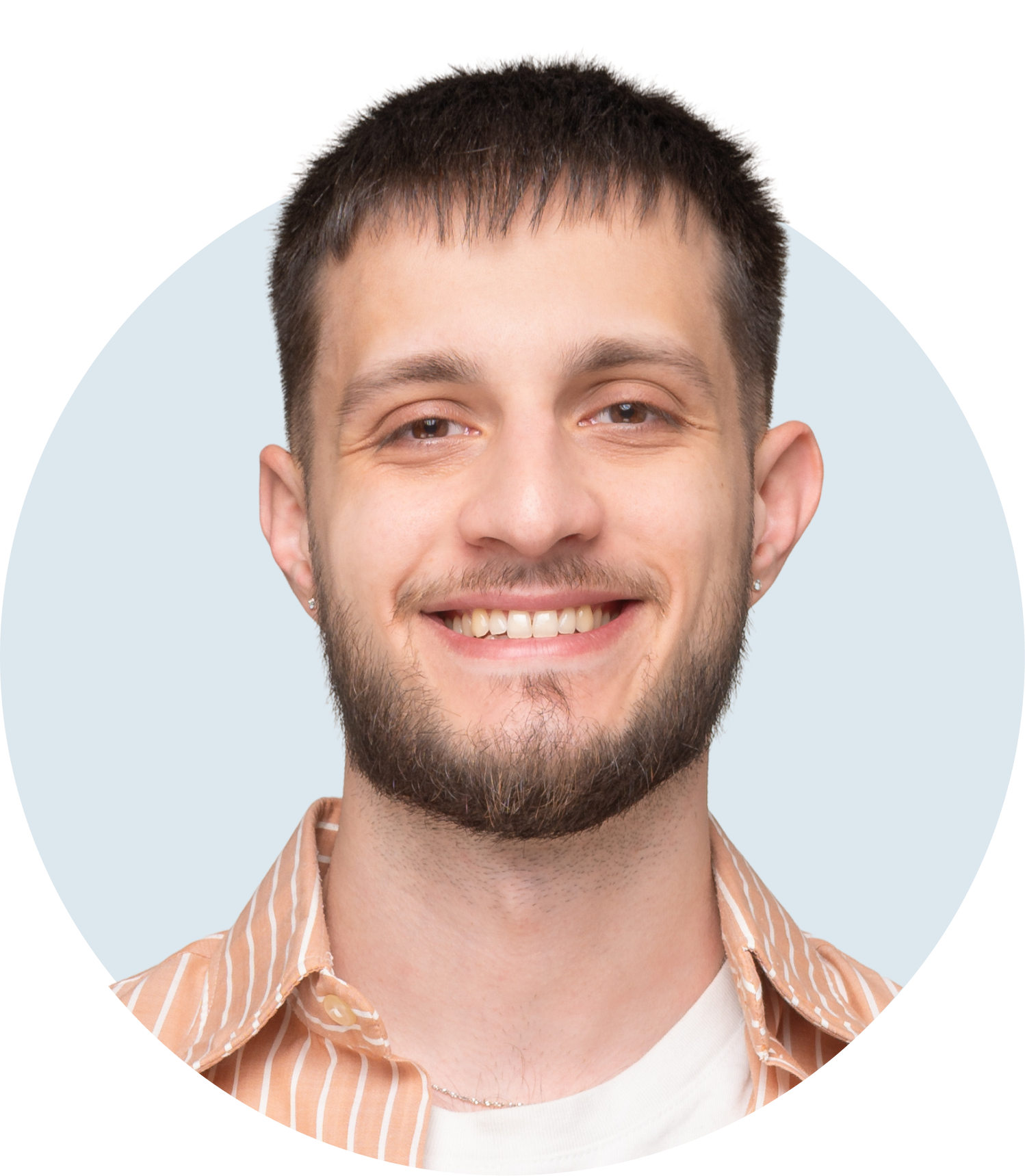 Smiling young man with short dark hair, beard, and earrings wearing a white t-shirt and orange striped shirt against a pale blue circular background.