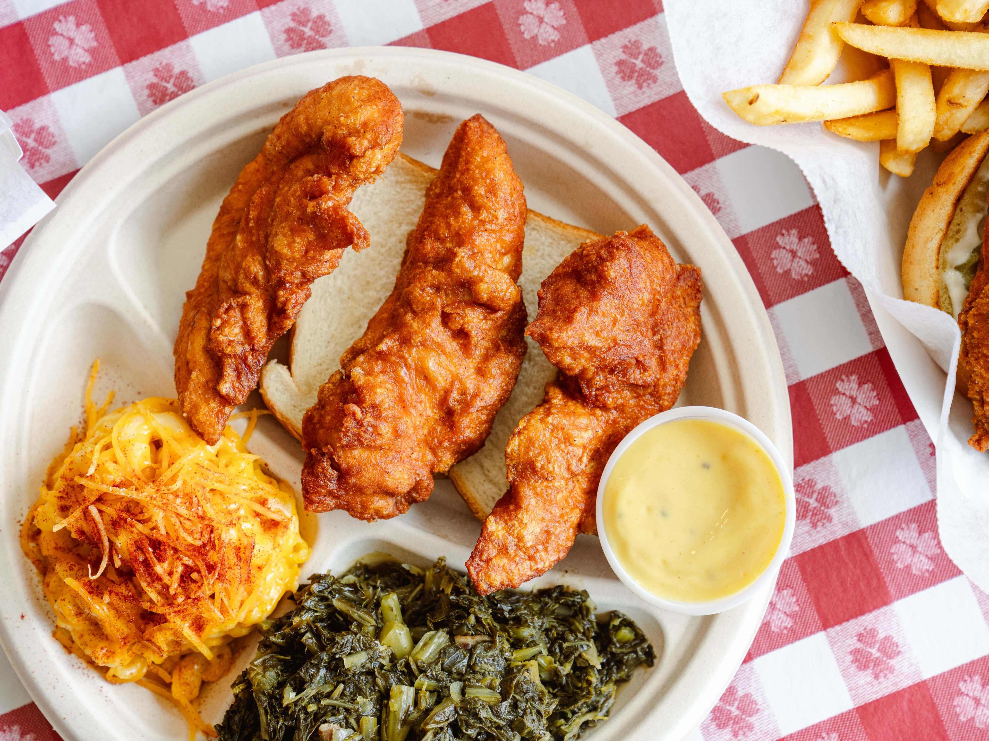 Close-up of fried chicken tenders, mac& cheese, greens.