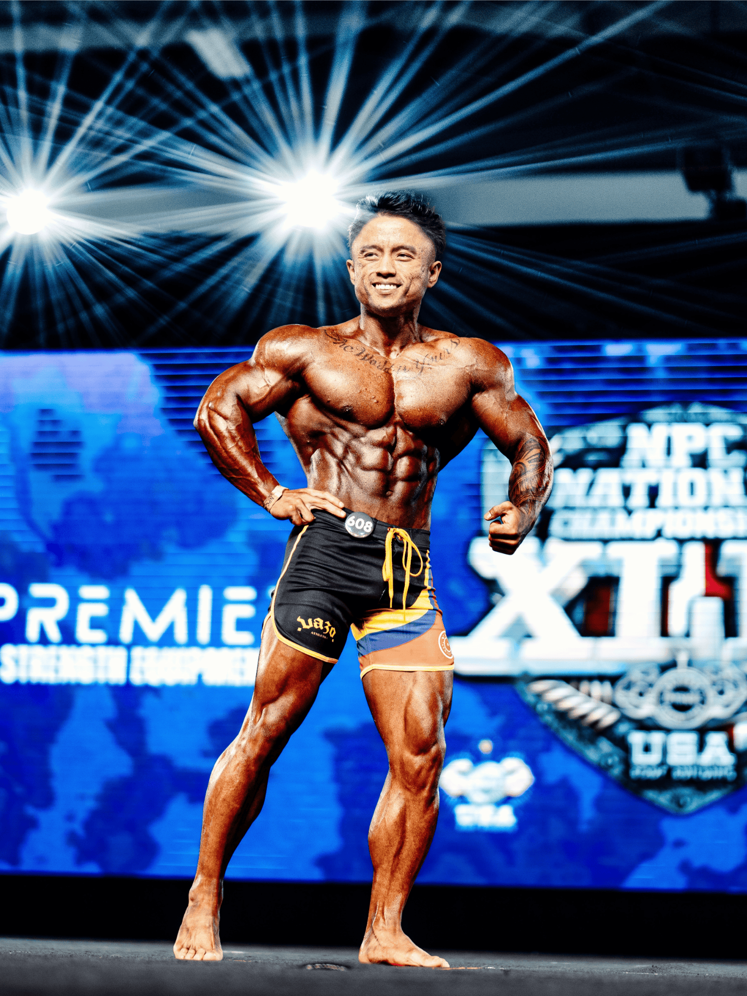 Bodybuilder posing on stage presenting muscular physique under bright lights at NPC National Championships.