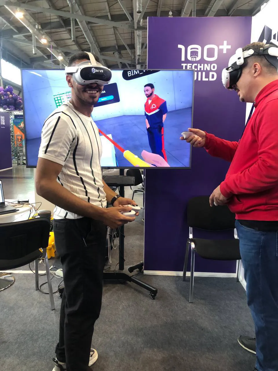 Two men in Virtual Reality headsets are viewing content at a conference