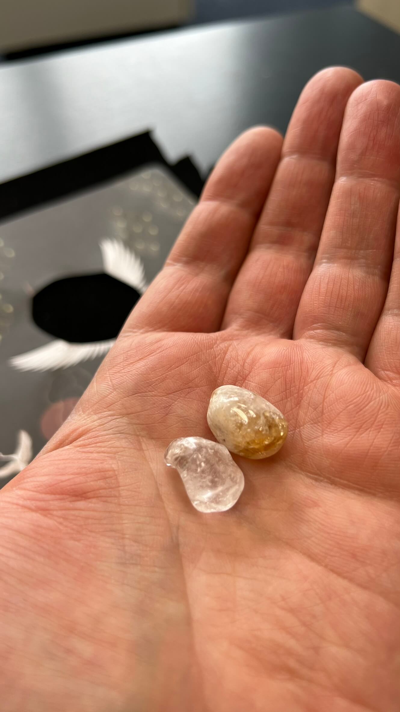Two tiny gemstones on a man's palm against the background of a black table