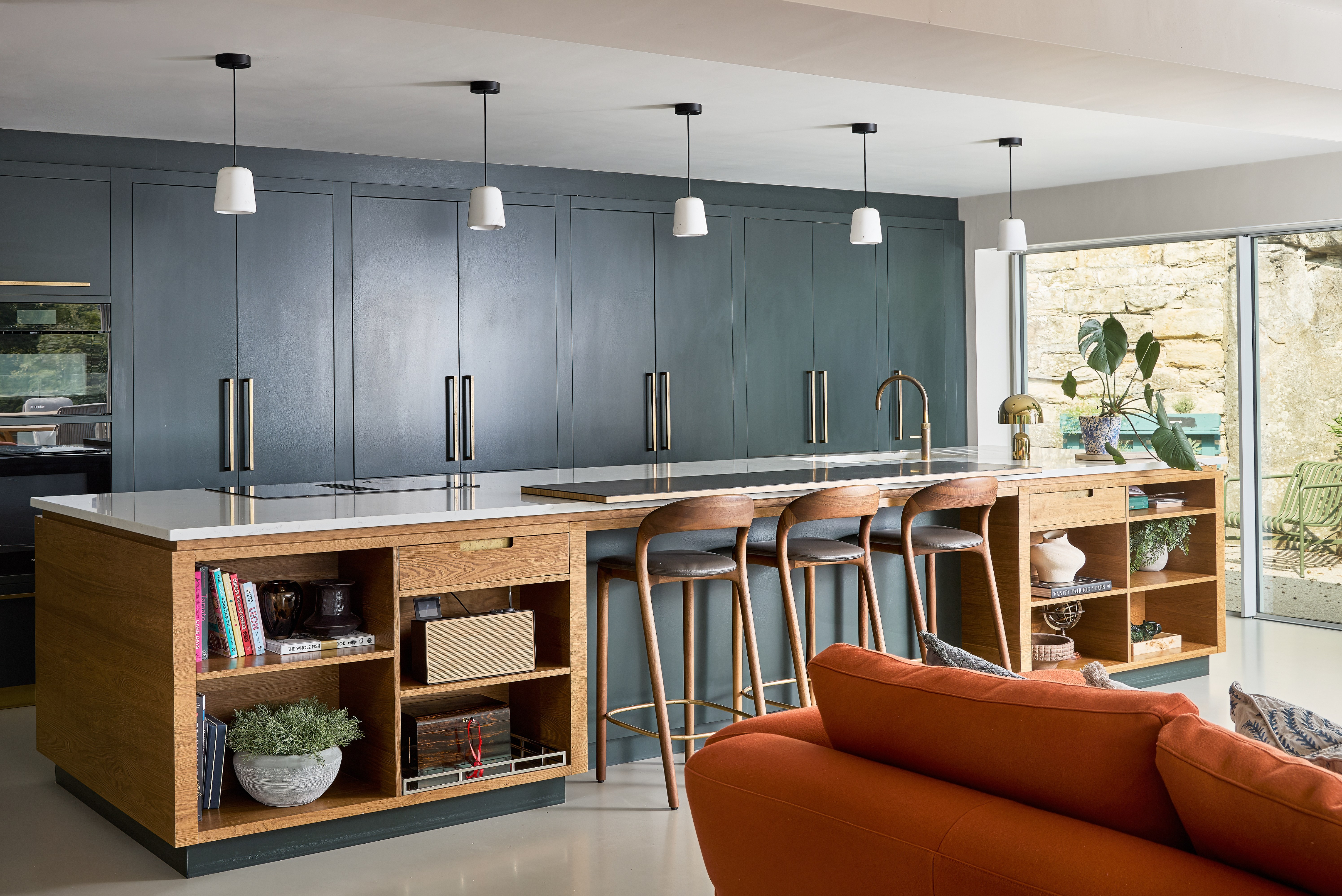 A bespoke kitchen with dark green painted cabinetry and a wooden kitchen island, with marble counter top