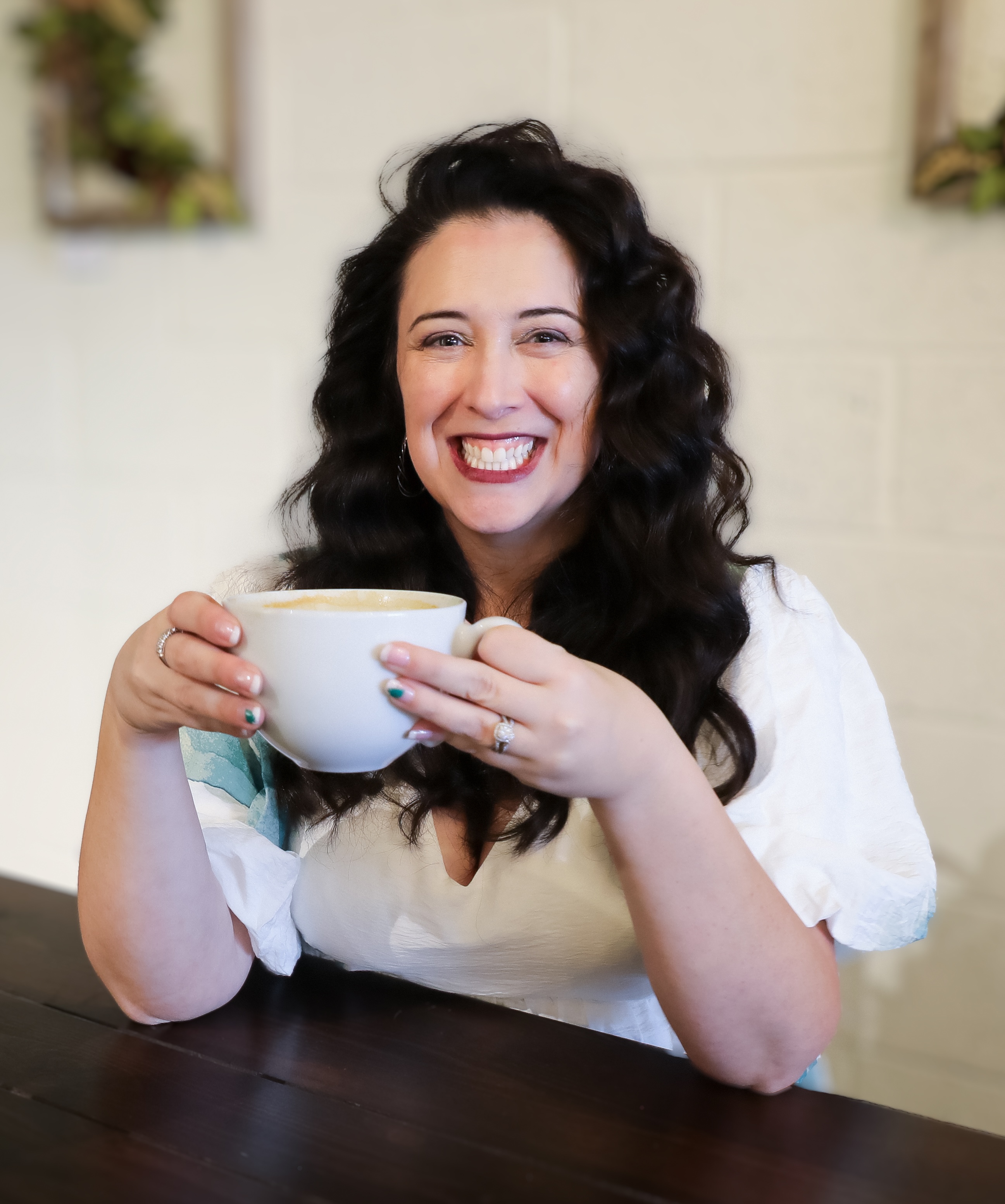 Smiling woman holding a white coffee mug at a wooden table