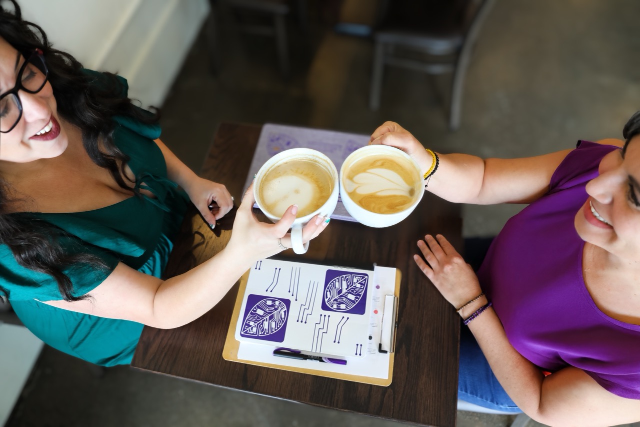 Two women drinking coffee and working together on a website design