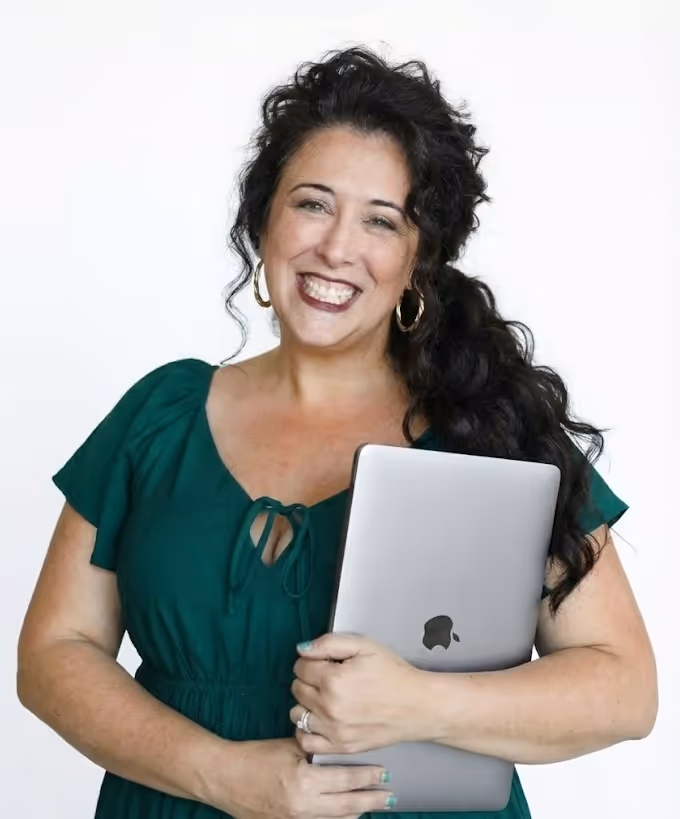 Lizzy Moffett smiling, holding MacBook in green dress against white background