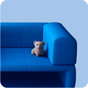 Small beige teddy bear sitting on a bright blue sofa against a light blue background.