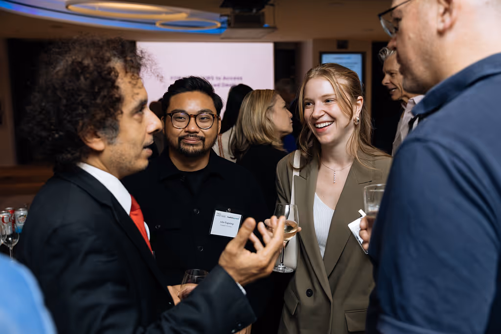 Group of venture capital professionals and startup founders networking at a social event, sharing insights and building relationships over drinks.