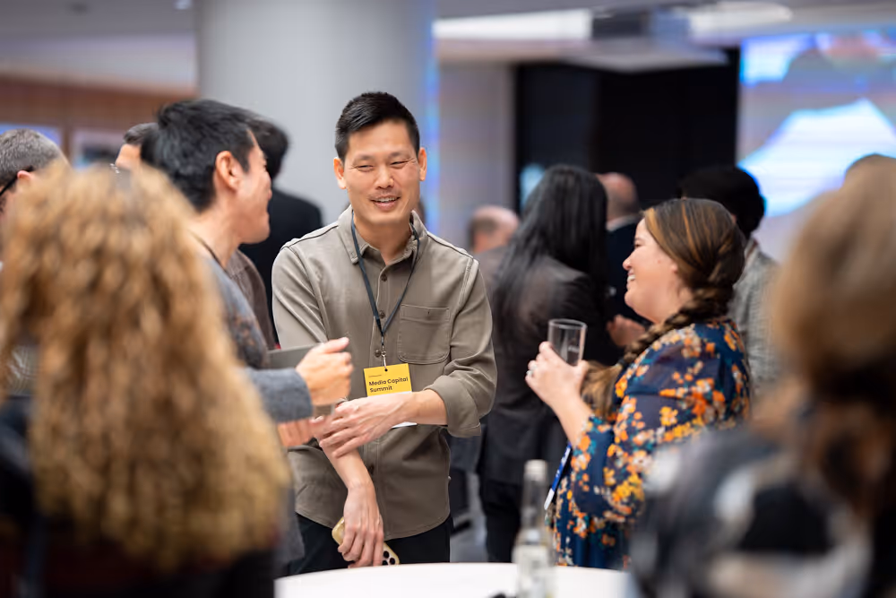 People networking and smiling during a social event or conference gathering indoors.