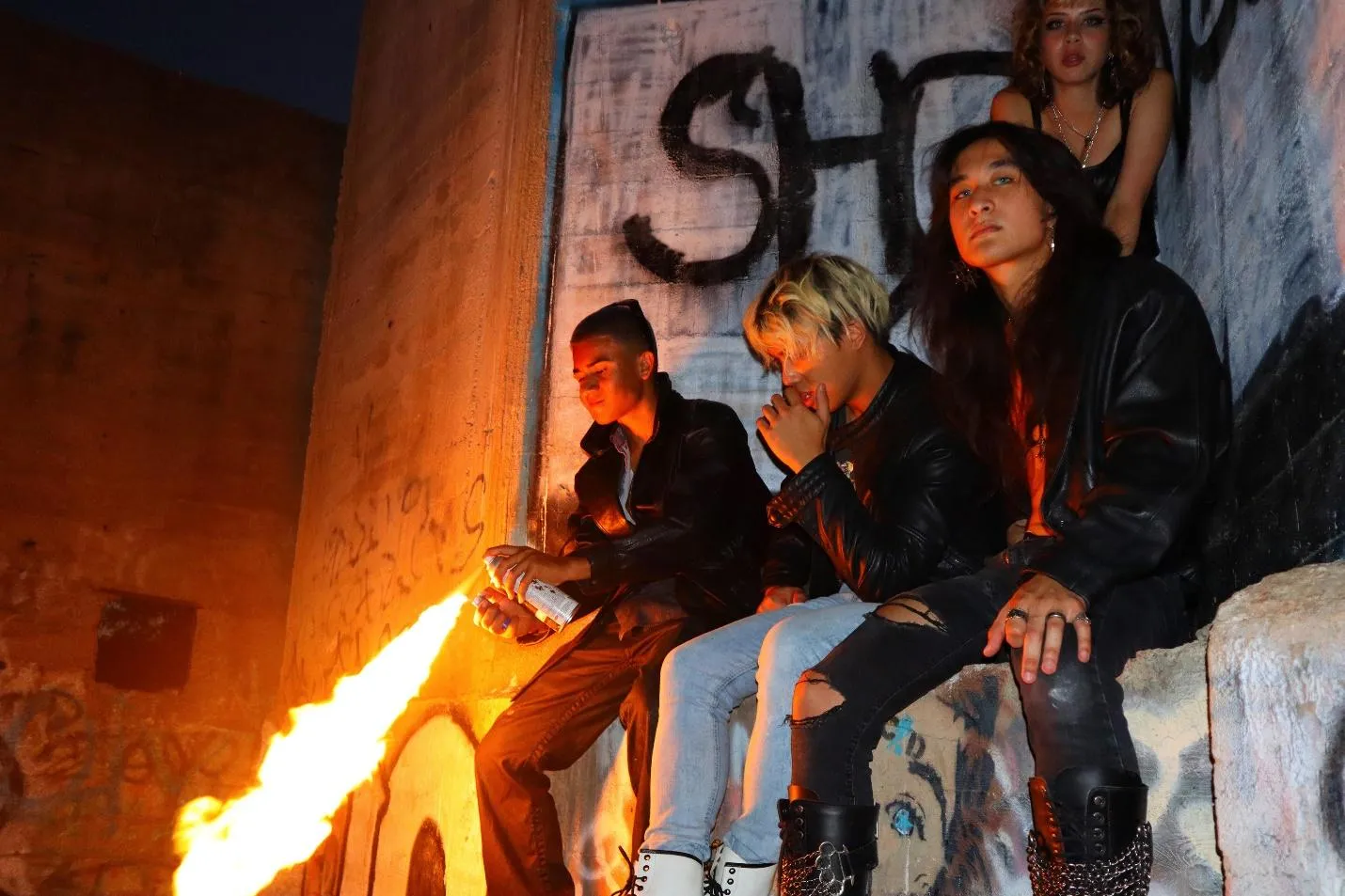 A group of people sitting on a bench by a fireDescription automatically generated with low confidence