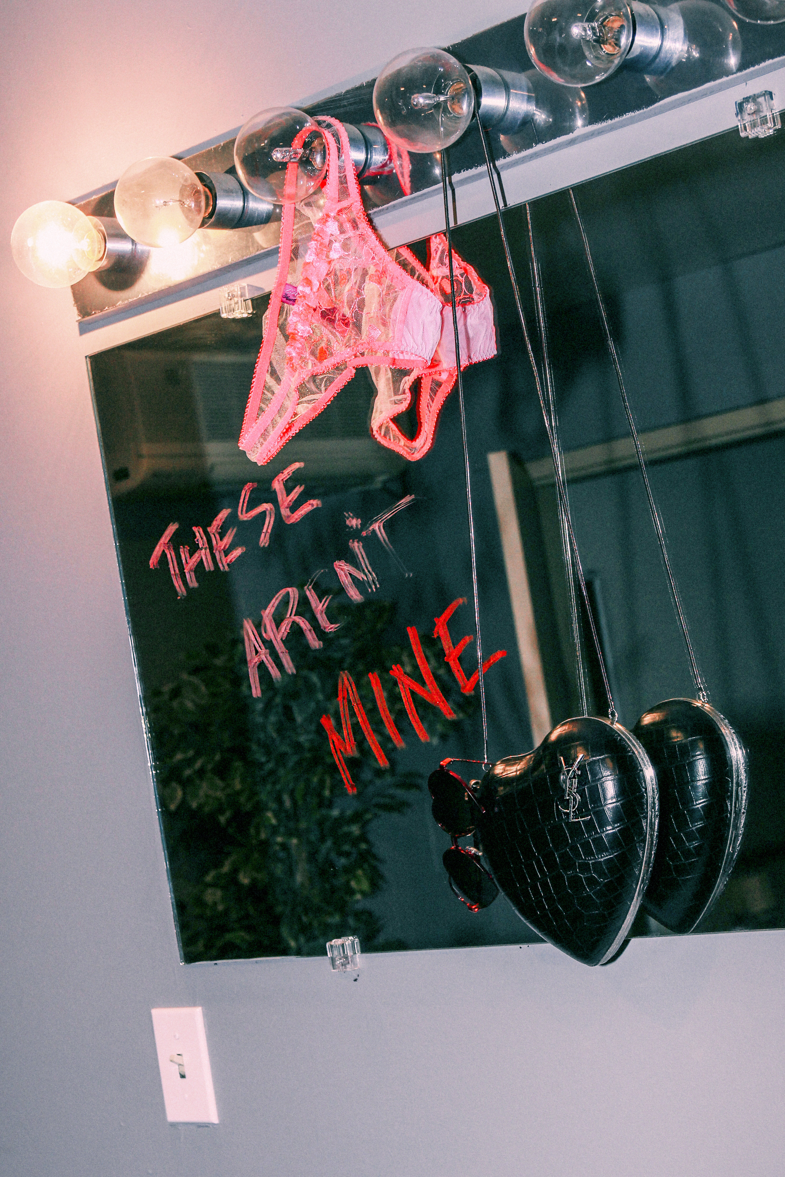 SAINT LAURENT BY ANTHONY VACCARELLO crocodile-embossed leather love box, WILDFOX ‘Lolita’ sunglasses, and L’AGENT BY AGENT PROVOCATEUR heart-embroidered tulle underwear. NARS velvet matte lip pencils in dirty mind and endangered red.
