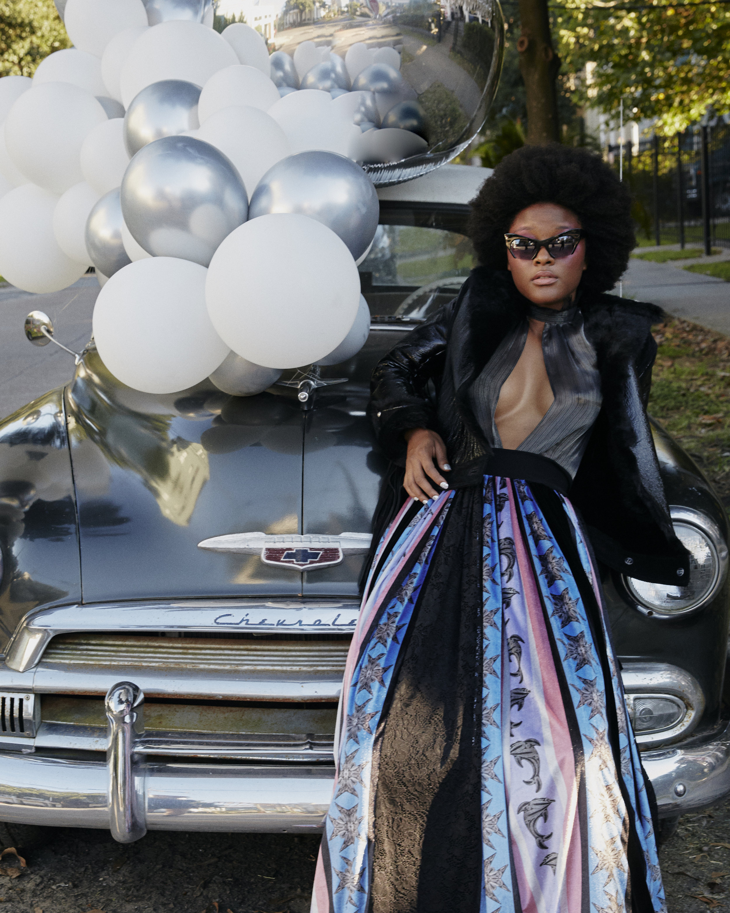 ALMAZ jacket and top, CHARLES AND RON skirt, and MIU MIU sunglasses