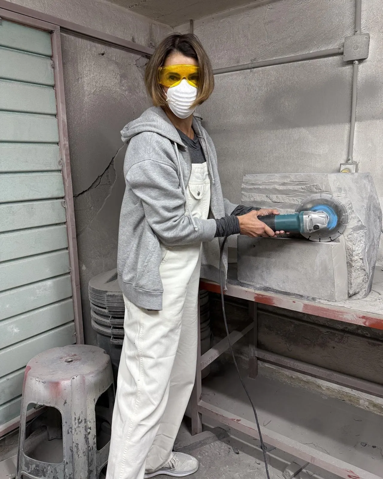 A person wearing goggles and a mask using a grinderAI-generated content may be incorrect.