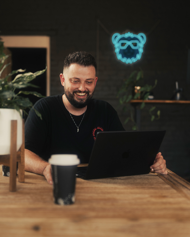 Robbie, Founder of Tudgee, smiling in front of a laptop having a client video call