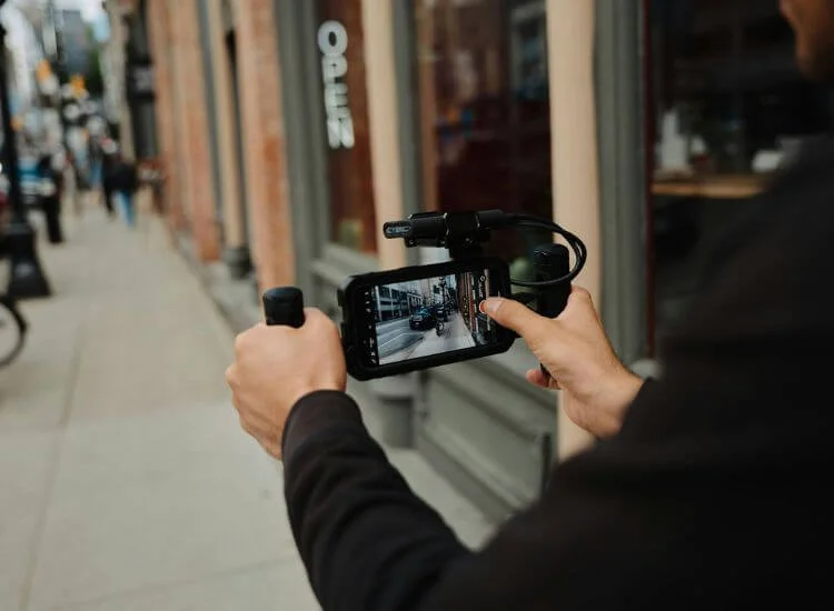 A travel vlogger capturing scenic B-roll footage in a busy street.