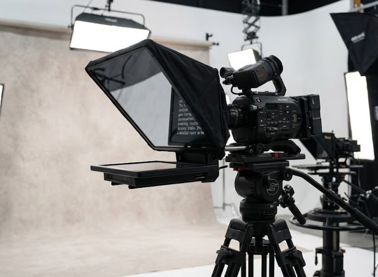 Camera-mounted teleprompter with beam-splitter mirror in a professional video studio setup
