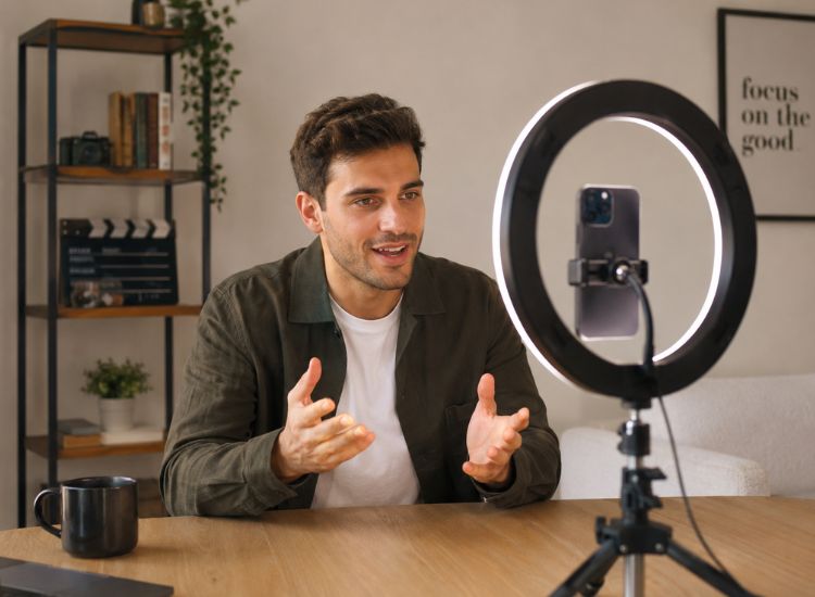 Content creator using a teleprompter app on a smartphone while recording a talking-head video