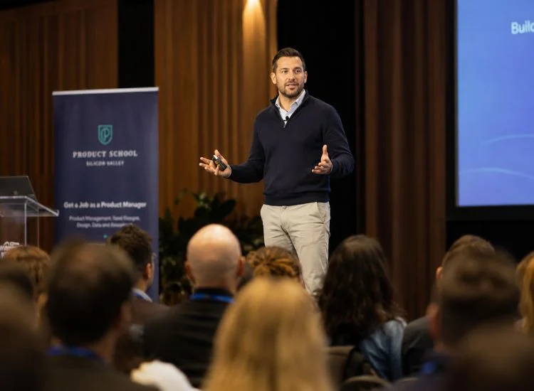 A public speaker with open posture and confident body language presenting to a live audience