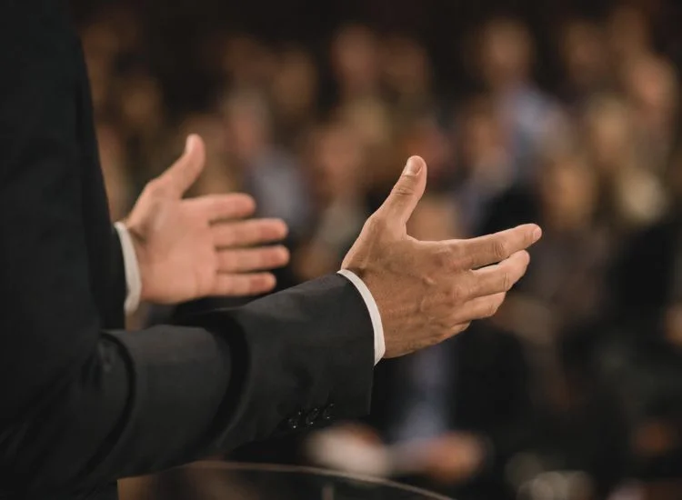 speaker using expressive hand gestures during a presentation, demonstrating effective body language