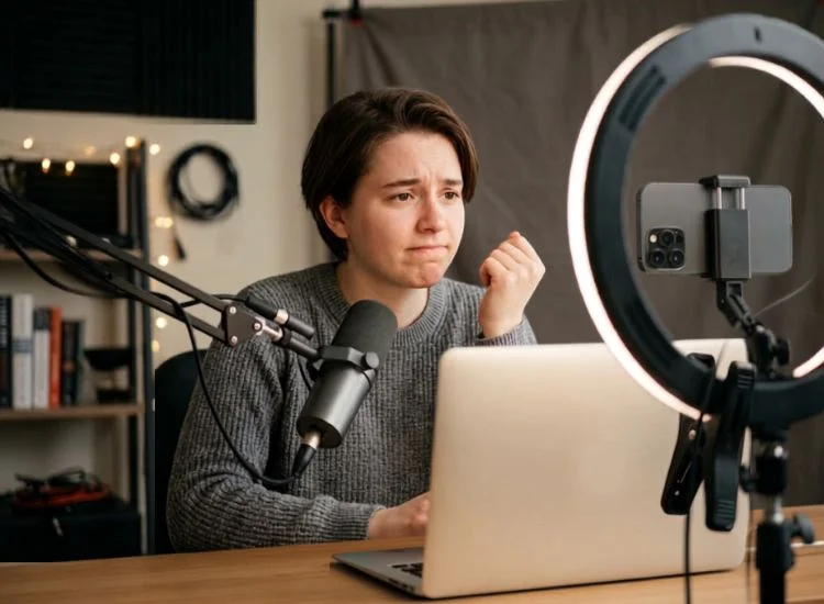 Content creator looking self-conscious while recording a video alone at a desk