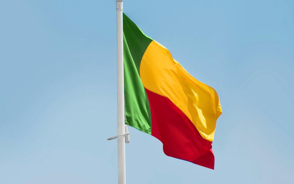Die Nationalflagge von Benin weht im Wind vor blauem Himmel