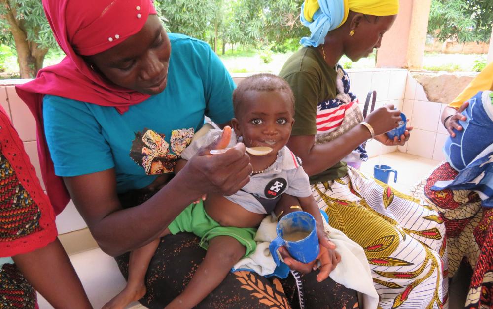 Junge Mutter füttert ihr Kind mit Brei – Hilfe gegen Mangelernährung in Burkina Faso.