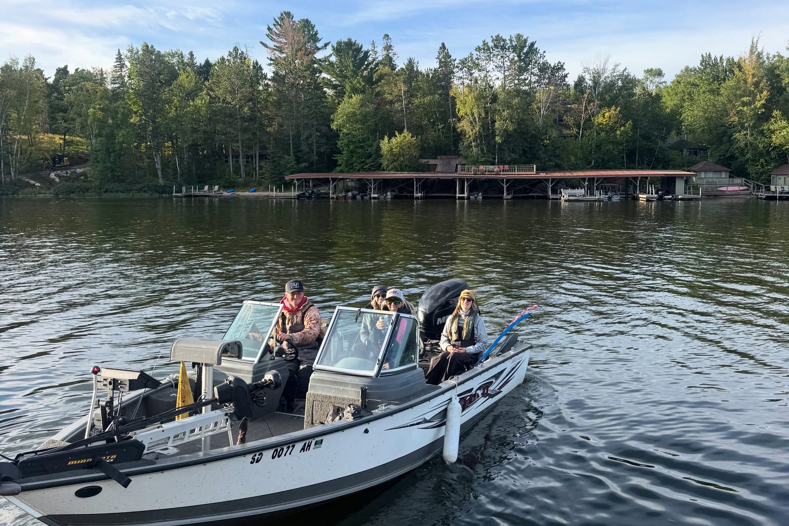 The fishing crew heading out by boat past the Ludlow's boathouse on Lake Vermilion
