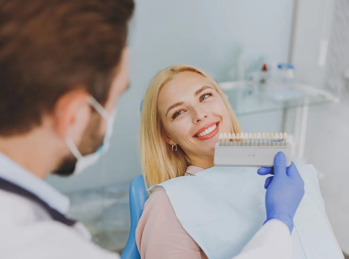 A dentist holds up a dental veneers shading guide up to the patient’s teeth at Hello Dental in Chelsea Heights.