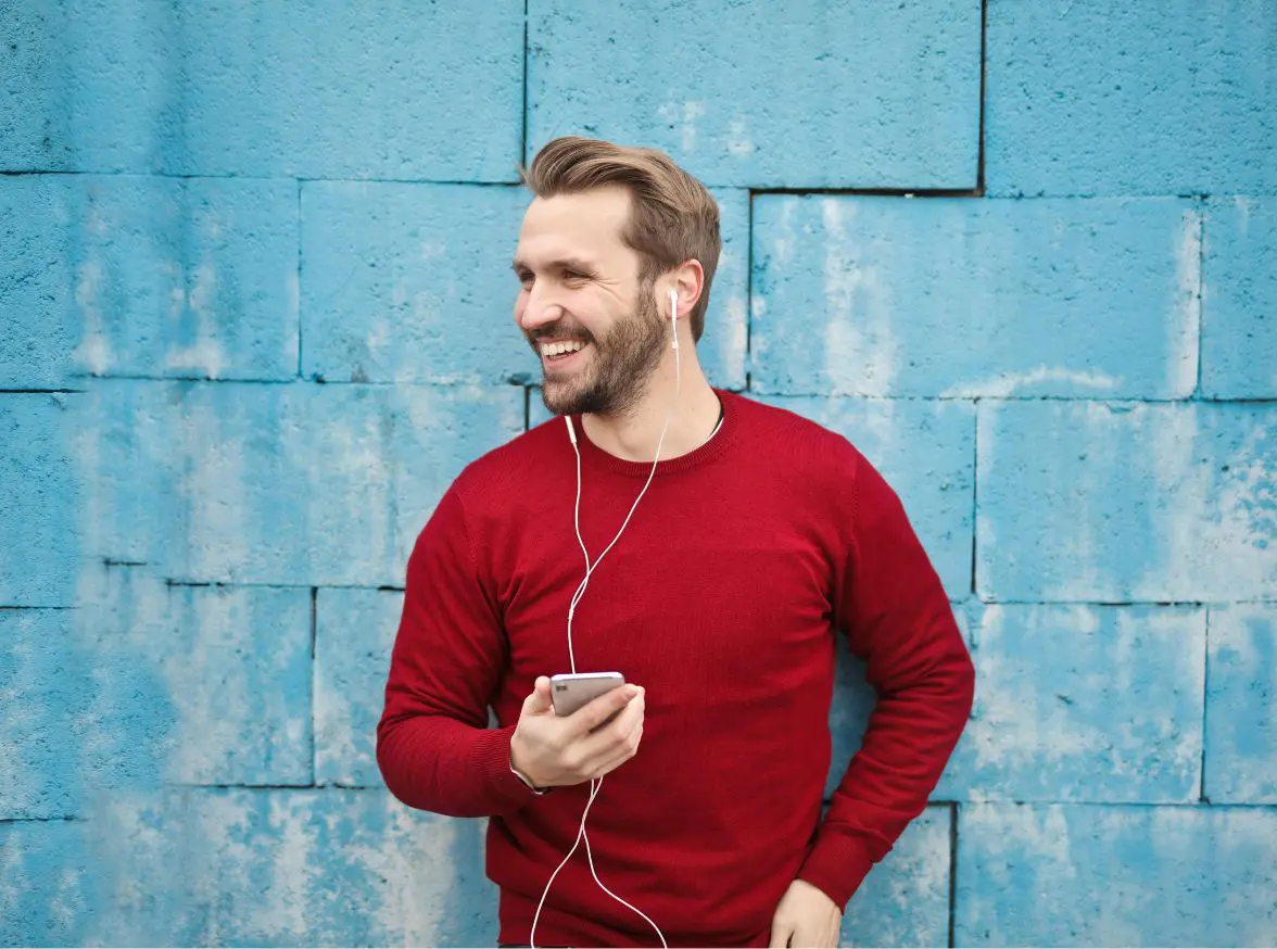 Man smiles happily while talking on the phone outdoors.