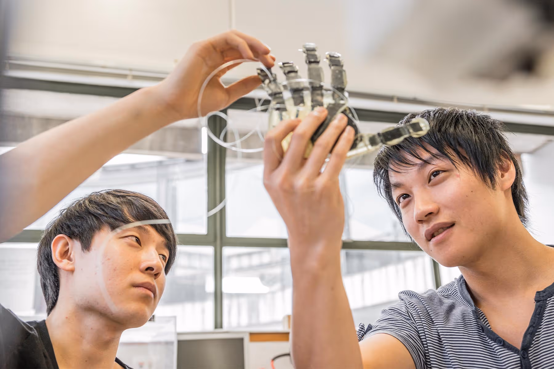 Two men inspecting a robotic hand