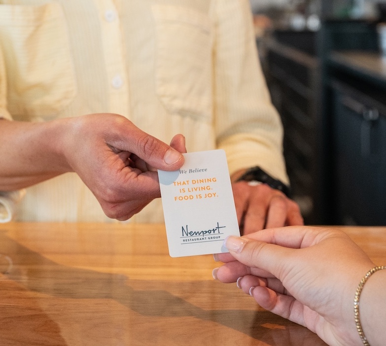 Guest holds a card that reads "We believe dining is living. Food is joy."