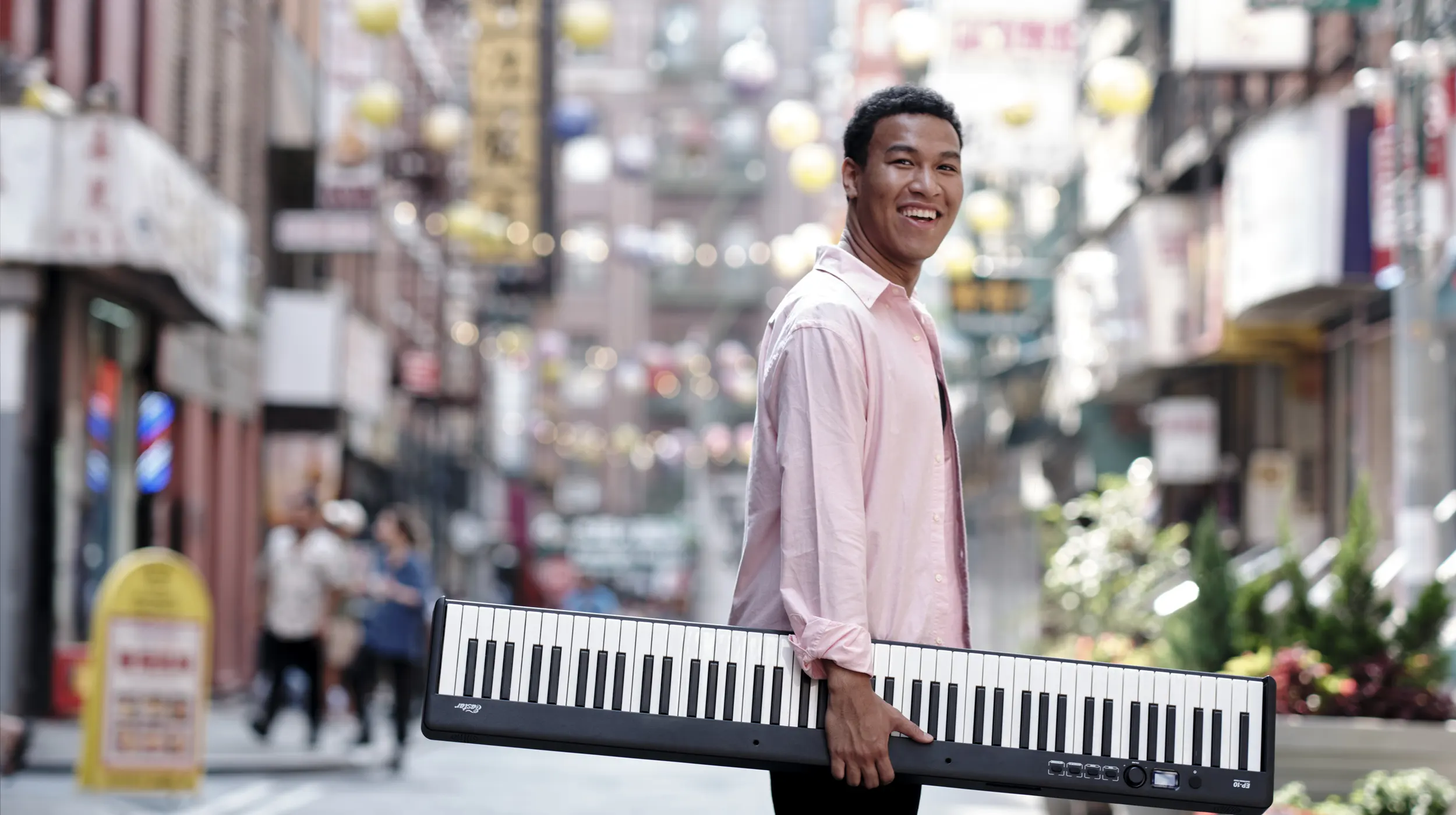Photo of Clayton walking across the street carrying a digital keyboard