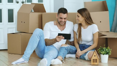 Couple looking at a house near a stack of cardboard boxes.