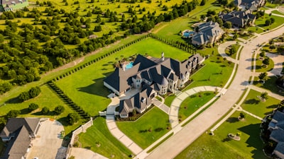 Victorian style luxury property on large green lawn with circular pathway.