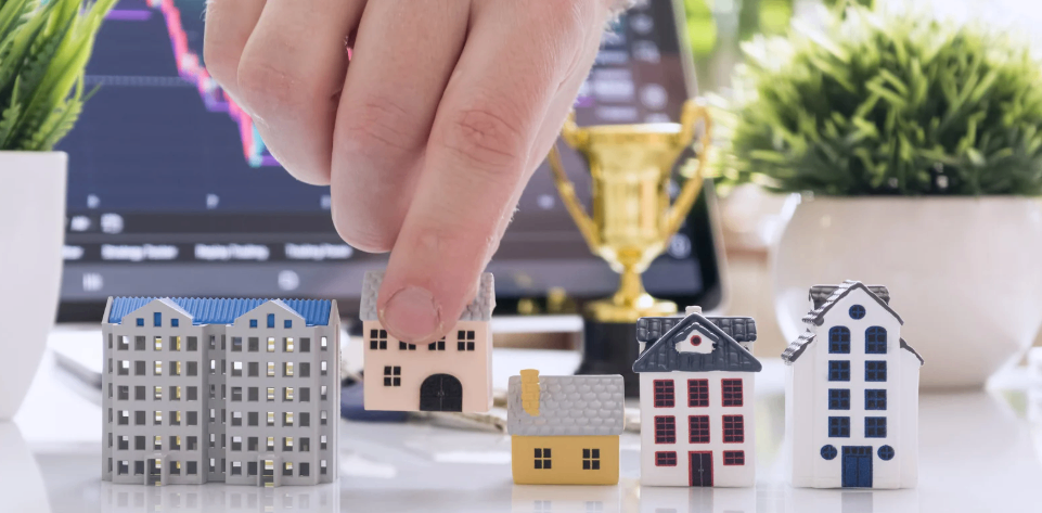 Image of a hand reaching to grab several different property type figurines.