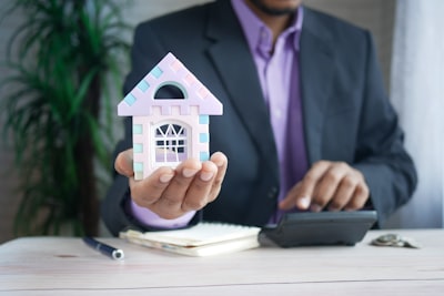 Business man holding out a house icon.