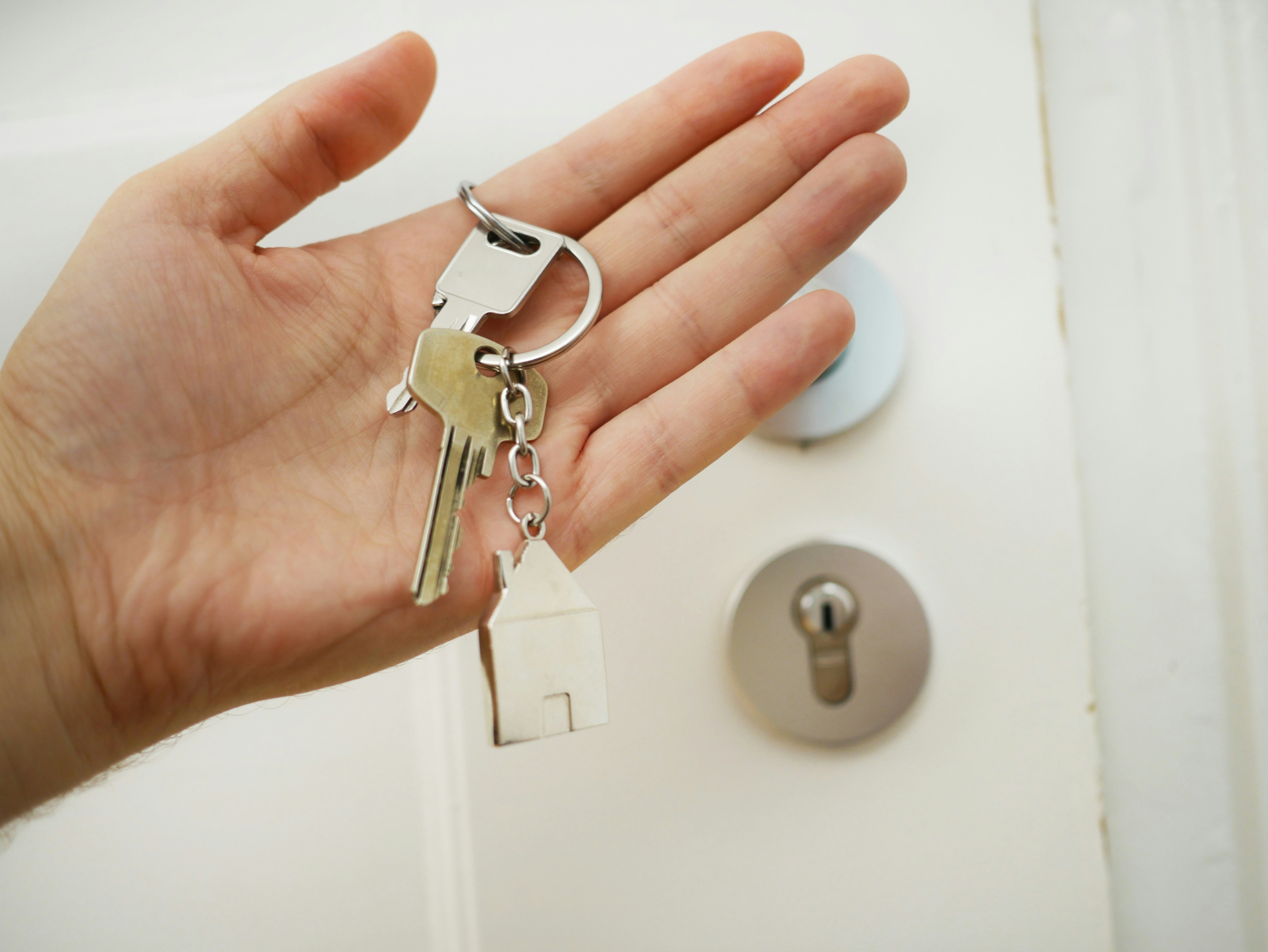 Hand holding keys with a house key charm. 