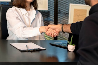 Two people shaking hands over a desk.
