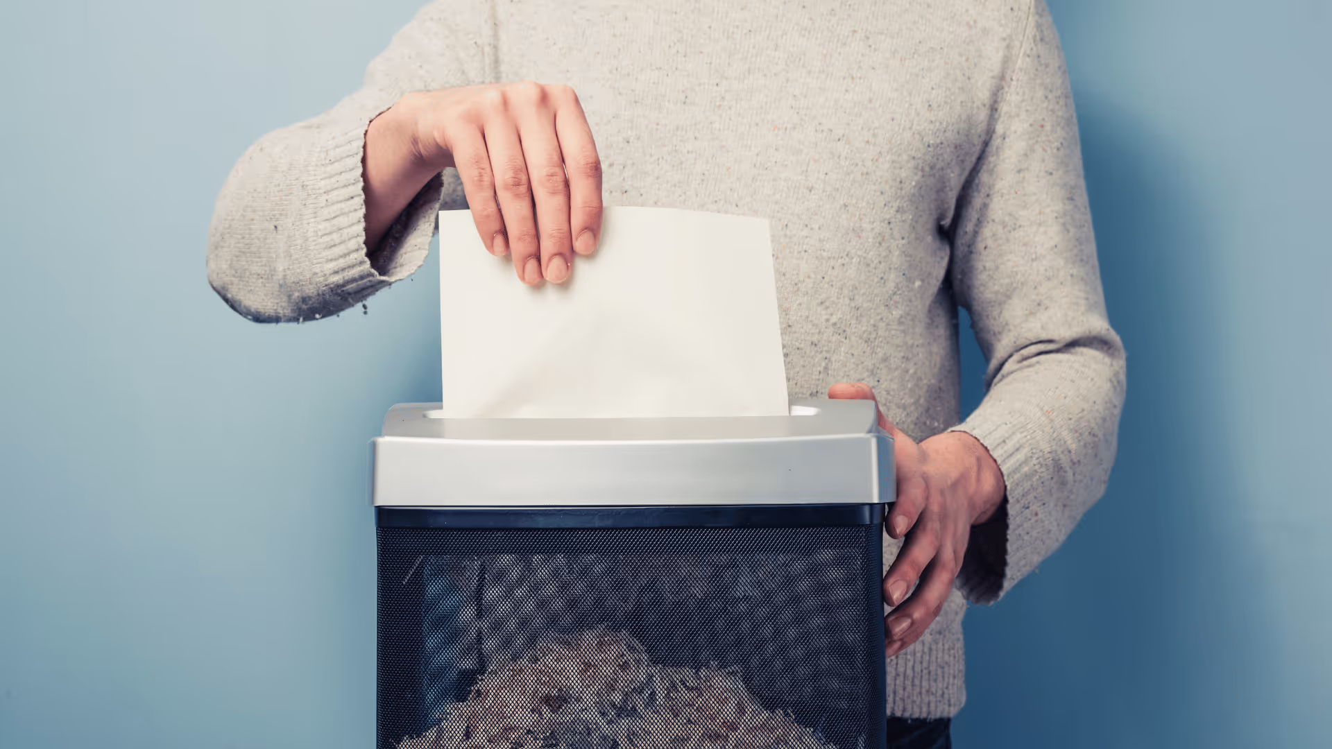 An individual holds a paper shredder, demonstrating the process of shredding paper.