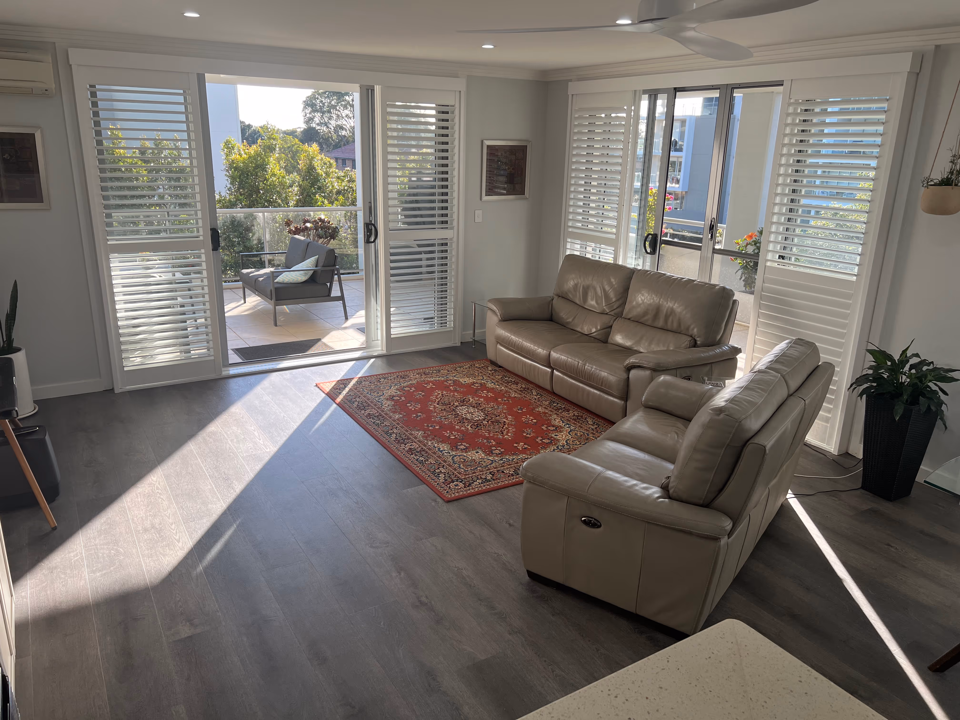 Compact living room opens directly to an outdoor area, unified by harmonious hybrid flooring.