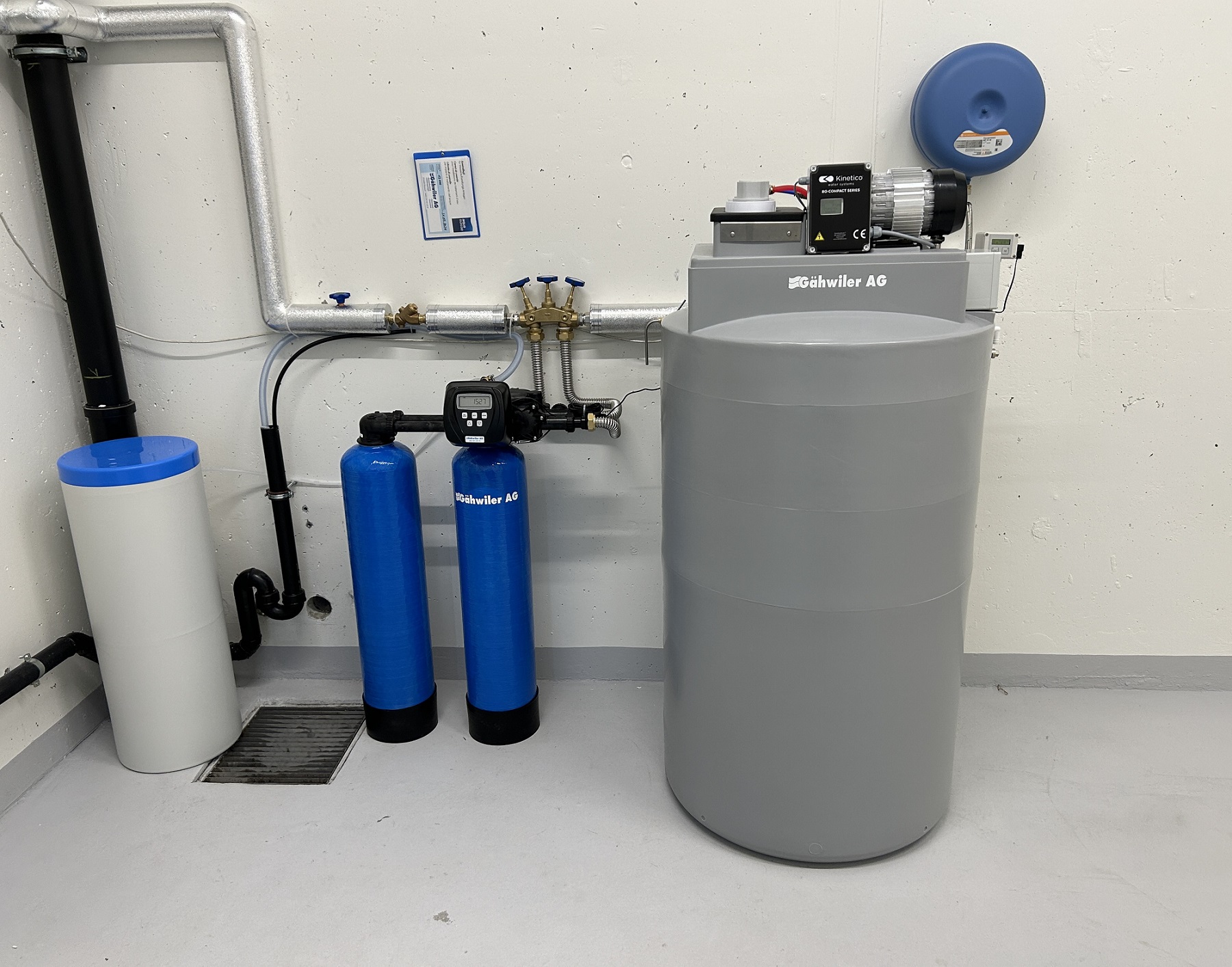 Ein Foto einer Pendel-Enthärtungsanlage und einer Osmoseanlage, welche an eine industrielle Waschmaschine von Miele angeschlossen ist