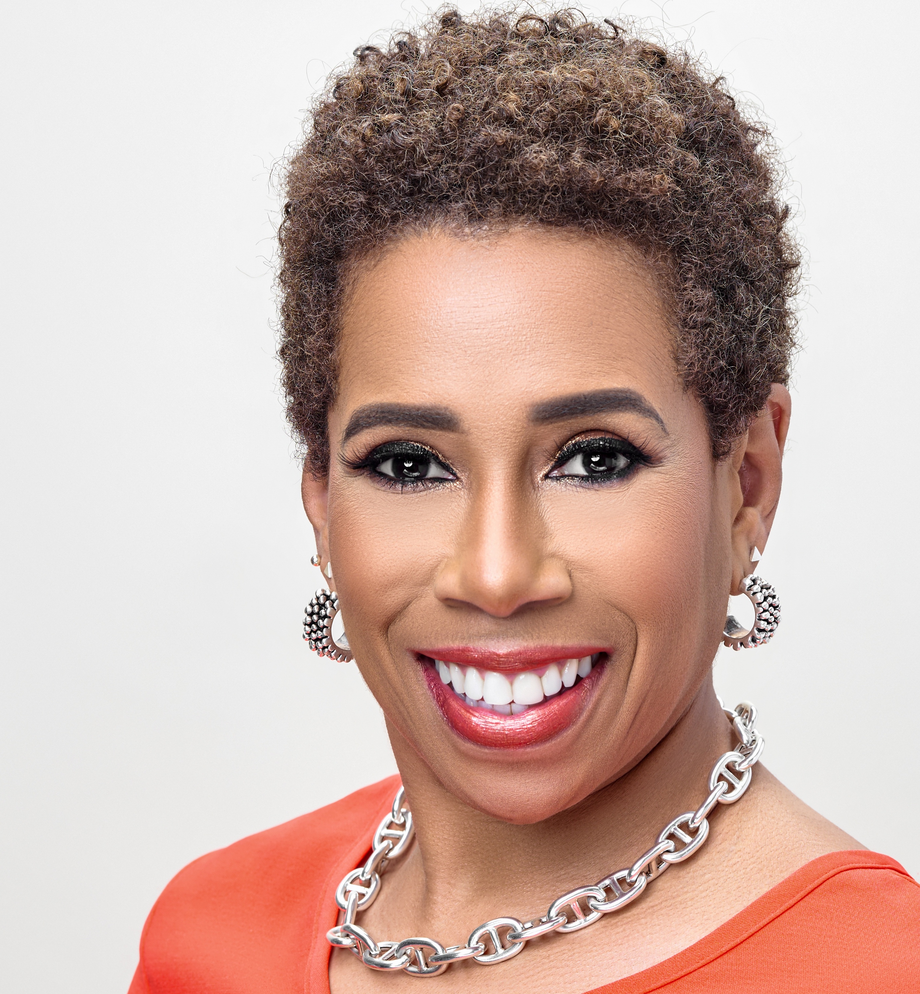 Headshot of Rena Henderson Mason, ESI Principal, wearing an orange top and silver necklace and earrings