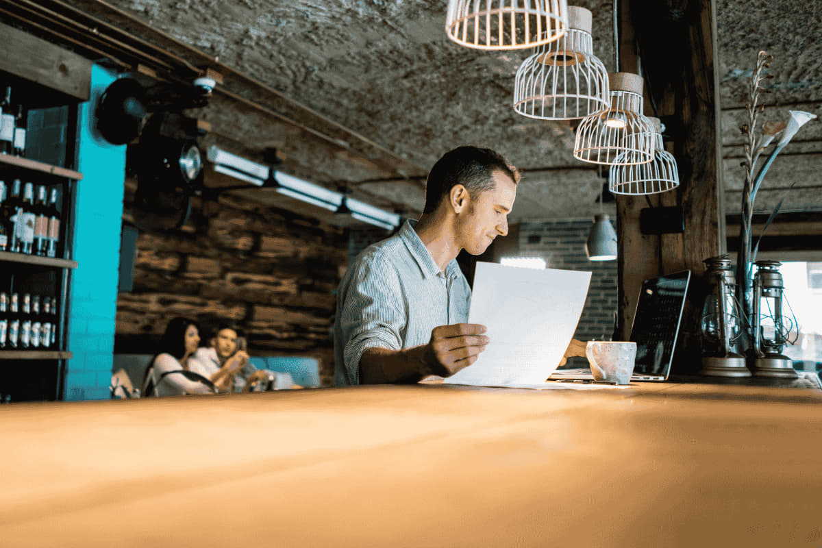 Professionnel de l’hospitality analysant une facture dans un café, illustrant les enjeux de la facturation électronique pour l’hôtellerie-restauration