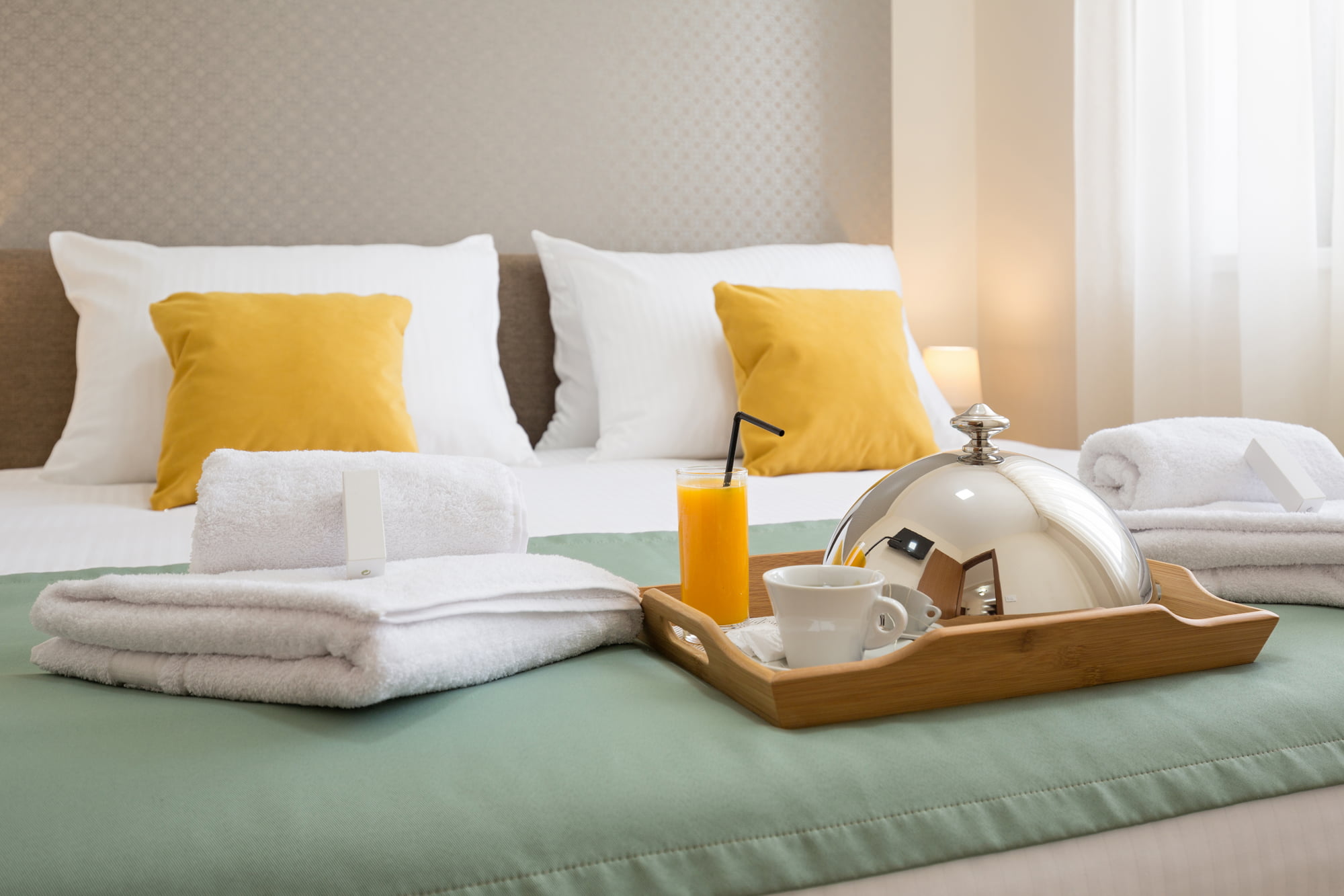 Petit-déjeuner servi en chambre d’hôtel avec plateau, jus d’orange, café et linge de bain, illustrant l’expérience client hôtelière